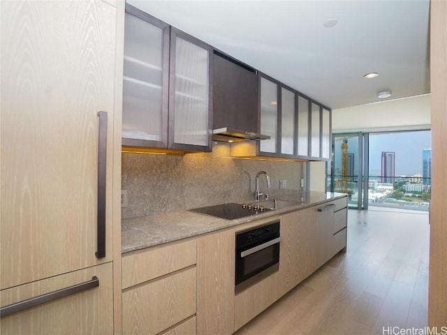 kitchen featuring stainless steel oven, backsplash, black electric stovetop, sink, and fridge