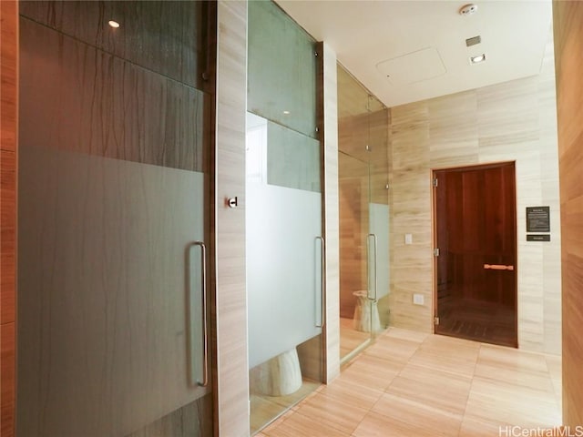 bathroom featuring tile patterned flooring, an enclosed shower, and tile walls