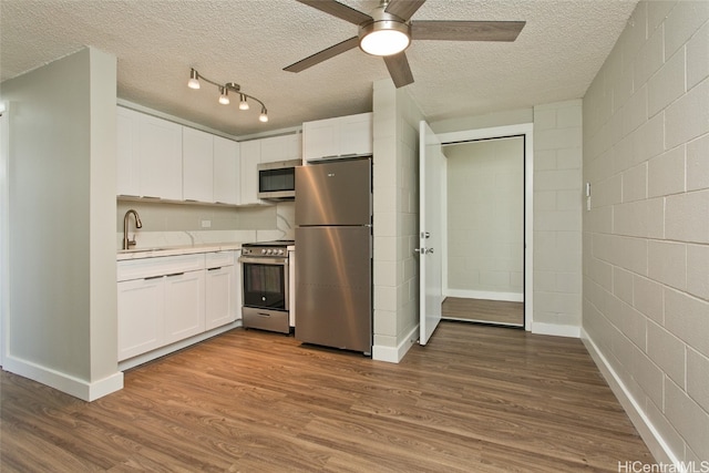 kitchen featuring white cabinetry, stainless steel appliances, wood-type flooring, and a textured ceiling