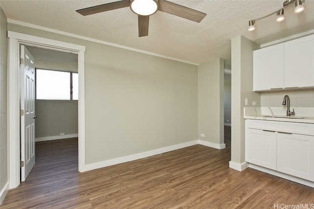 kitchen featuring dark wood-type flooring, a textured ceiling, white cabinetry, and sink