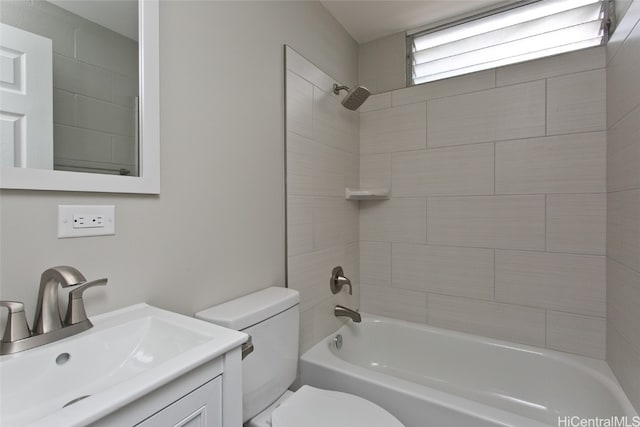 full bathroom featuring vanity, tiled shower / bath combo, and toilet