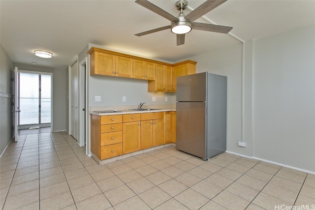 kitchen featuring ceiling fan, light tile patterned flooring, stainless steel refrigerator, and sink