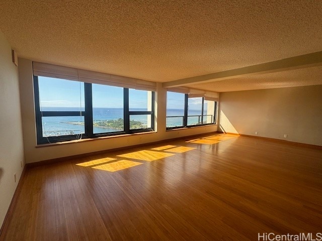 spare room featuring a water view, a textured ceiling, and light hardwood / wood-style flooring