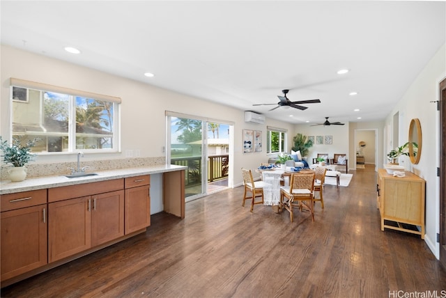 kitchen featuring ceiling fan, dark hardwood / wood-style flooring, light stone countertops, a wall mounted air conditioner, and sink