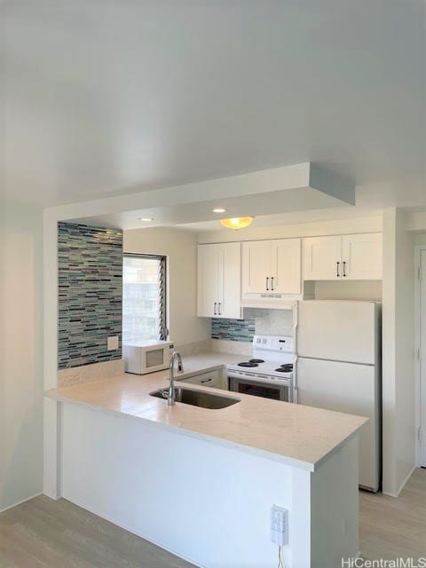 kitchen with white appliances, kitchen peninsula, white cabinets, and sink