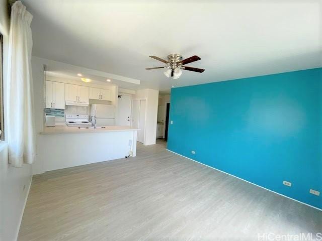 unfurnished living room with a ceiling fan, a sink, and light wood-style flooring