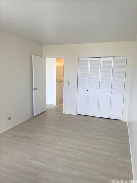 unfurnished bedroom with light wood-type flooring and a closet