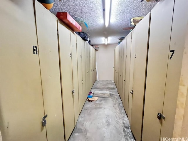 corridor with a textured ceiling and unfinished concrete flooring