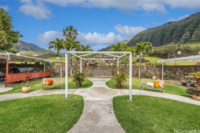 view of property's community with a mountain view, a lawn, and a pergola