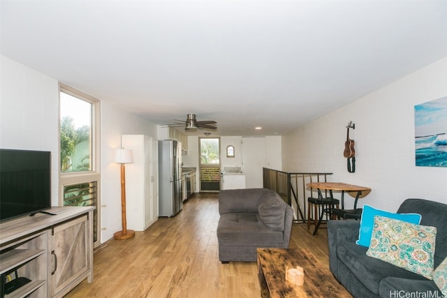 living room with light hardwood / wood-style floors, ceiling fan, and a wealth of natural light