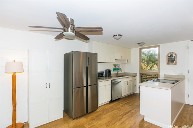 kitchen featuring appliances with stainless steel finishes, sink, white cabinetry, ceiling fan, and light hardwood / wood-style flooring