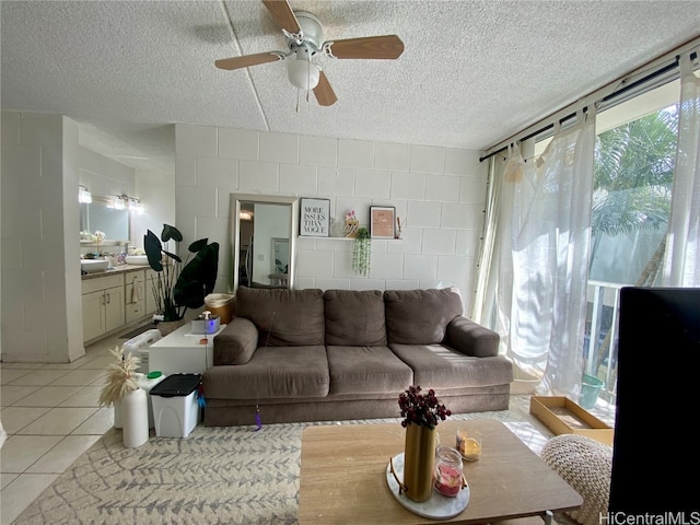 living room with a textured ceiling, light tile patterned floors, and ceiling fan