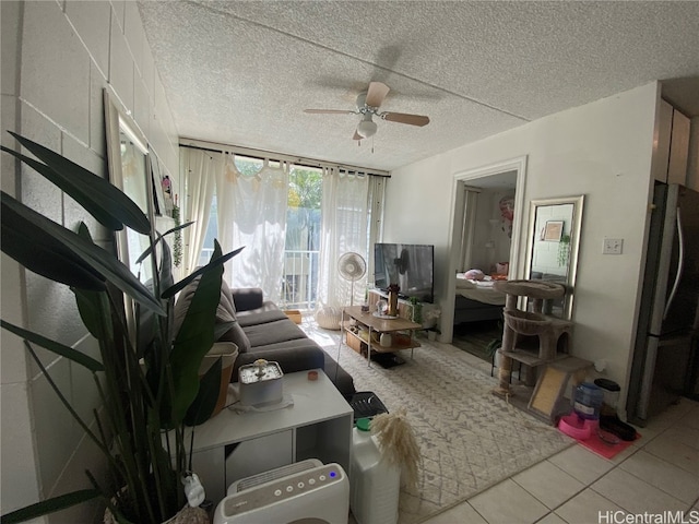 living room with ceiling fan, a textured ceiling, and light tile patterned floors