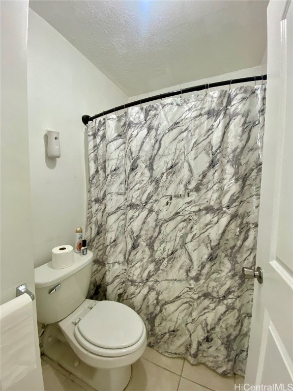 bathroom with toilet, a textured ceiling, and tile patterned flooring