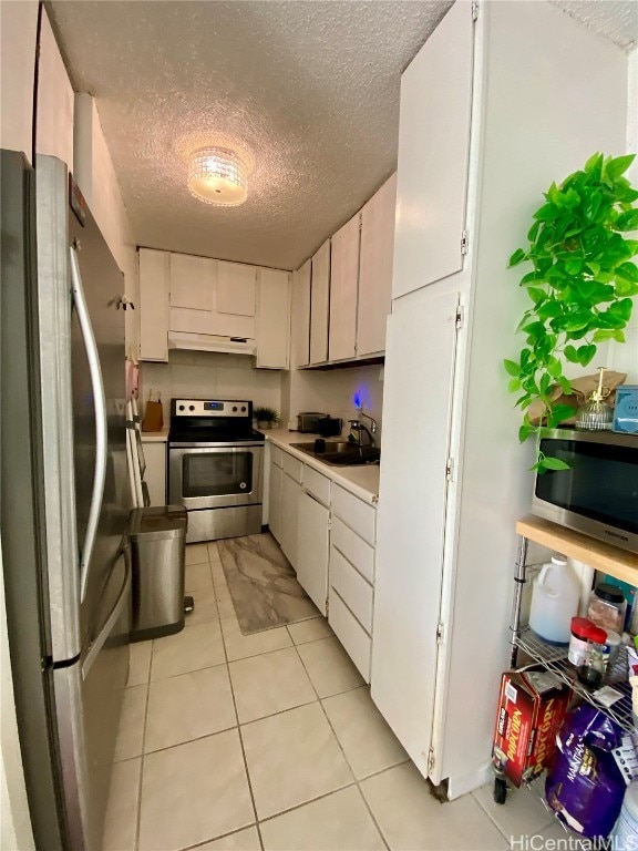 kitchen with appliances with stainless steel finishes, a textured ceiling, white cabinetry, and extractor fan