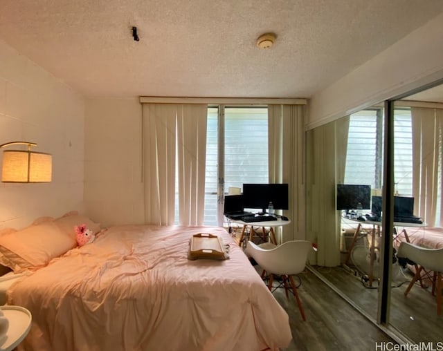 bedroom with a textured ceiling and wood-type flooring