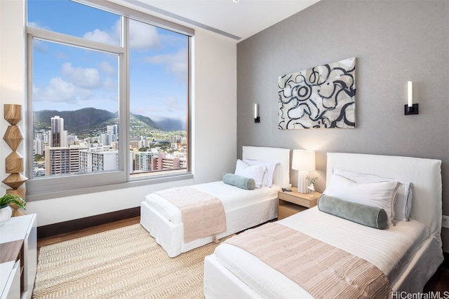 bedroom with a mountain view, multiple windows, and light wood-type flooring