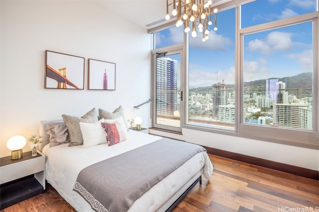 bedroom with hardwood / wood-style floors, multiple windows, and a chandelier