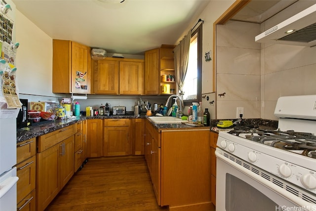 kitchen featuring exhaust hood, white gas stove, dark stone counters, dark hardwood / wood-style floors, and sink