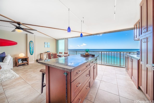 kitchen with a kitchen island, pendant lighting, rail lighting, a water view, and ceiling fan