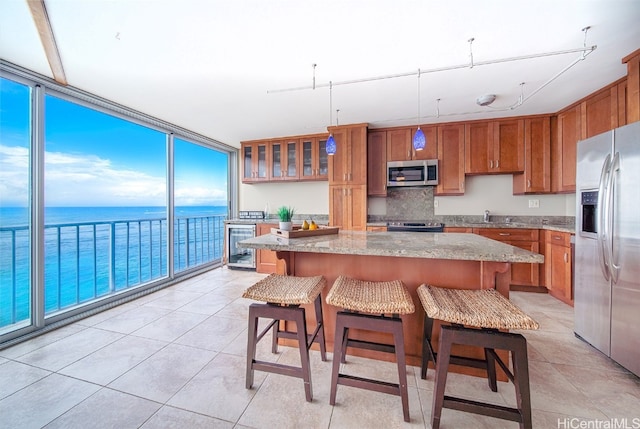 kitchen featuring appliances with stainless steel finishes, light stone counters, a water view, and a kitchen island