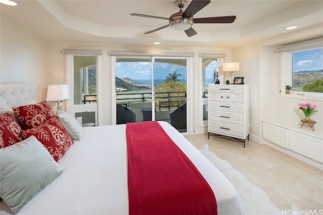 bedroom featuring access to exterior, a tray ceiling, and ceiling fan