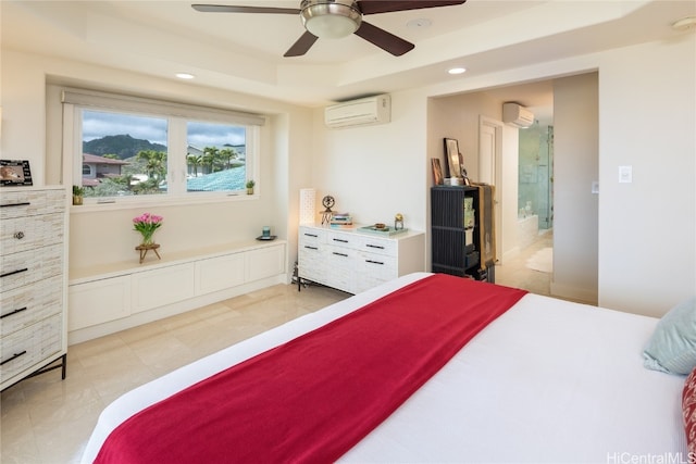 bedroom with ensuite bath, a wall unit AC, a tray ceiling, and ceiling fan