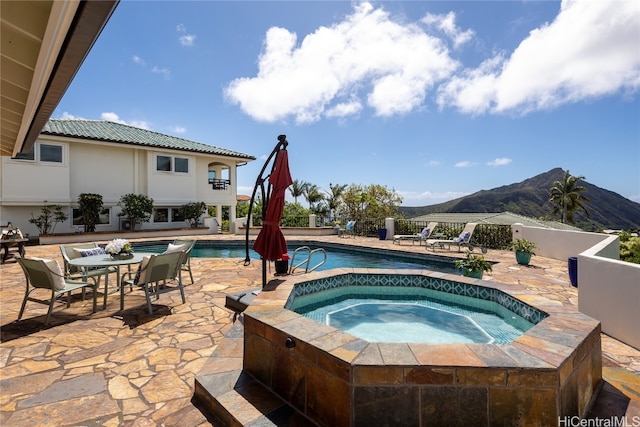 view of swimming pool featuring a patio area, a mountain view, and an in ground hot tub