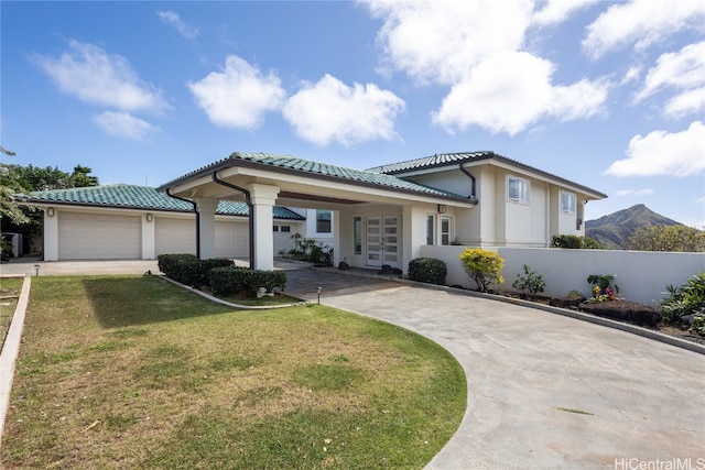 view of front facade featuring a garage, a mountain view, and a front lawn