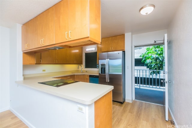 kitchen featuring appliances with stainless steel finishes, kitchen peninsula, sink, and light hardwood / wood-style flooring