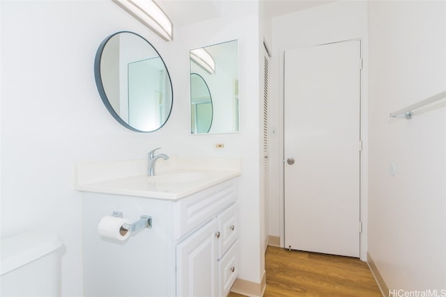 bathroom with toilet, vanity, and wood-type flooring