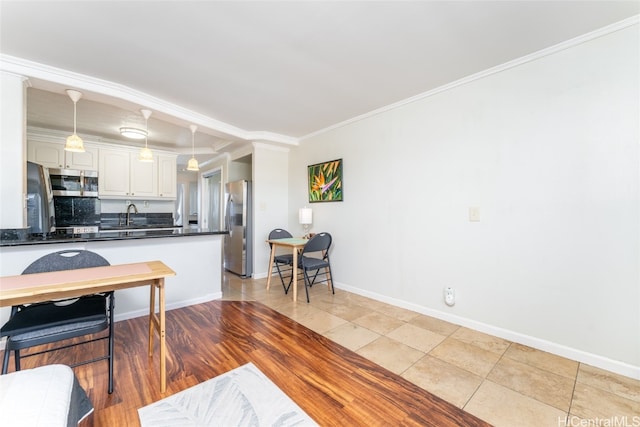 kitchen featuring tasteful backsplash, white cabinetry, stainless steel appliances, decorative light fixtures, and ornamental molding