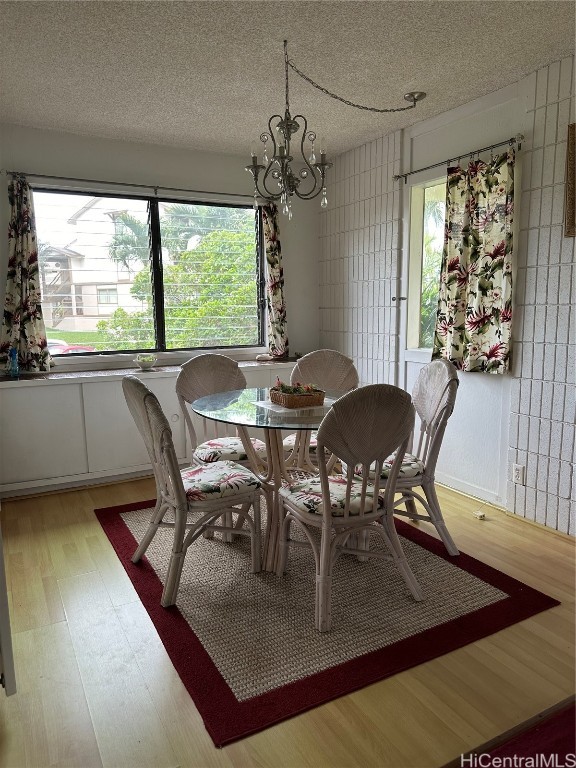 dining area with light hardwood / wood-style flooring, a textured ceiling, and a notable chandelier