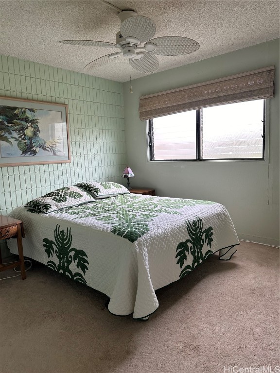 bedroom featuring a textured ceiling, multiple windows, carpet flooring, and ceiling fan