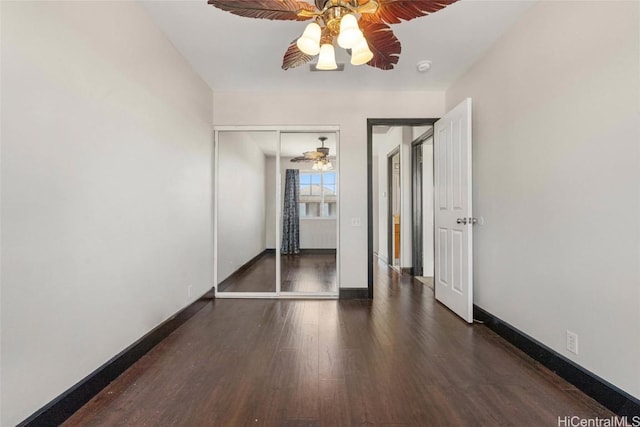 unfurnished bedroom with ceiling fan, dark wood-type flooring, and a closet