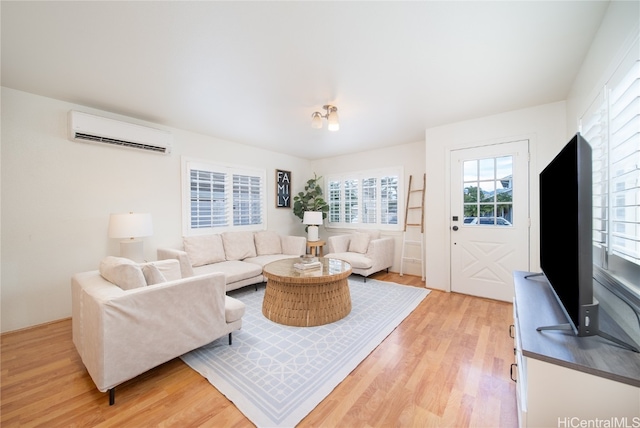 living room with an AC wall unit and light wood-type flooring