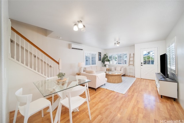 living room with light wood-type flooring and a wall unit AC