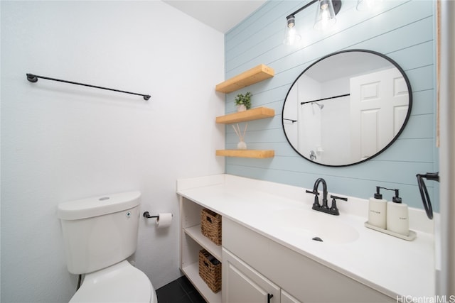 bathroom with vanity, toilet, and wood walls