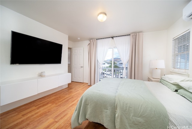 bedroom featuring a wall mounted air conditioner, access to outside, and light wood-type flooring