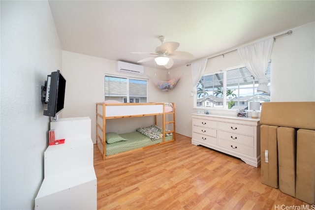 bedroom with an AC wall unit, light wood-type flooring, and ceiling fan