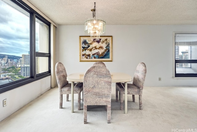 carpeted dining area featuring a wealth of natural light, a textured ceiling, and a chandelier