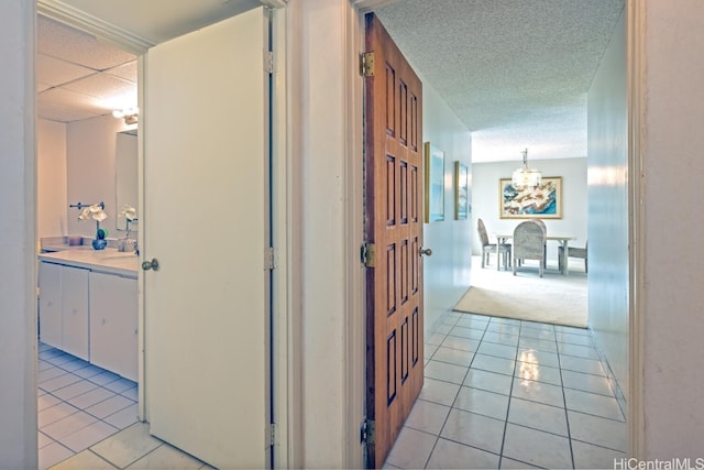 hall with sink, light tile patterned flooring, and an inviting chandelier