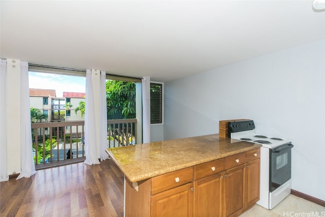 kitchen with white range with electric stovetop, light stone countertops, and wood-type flooring