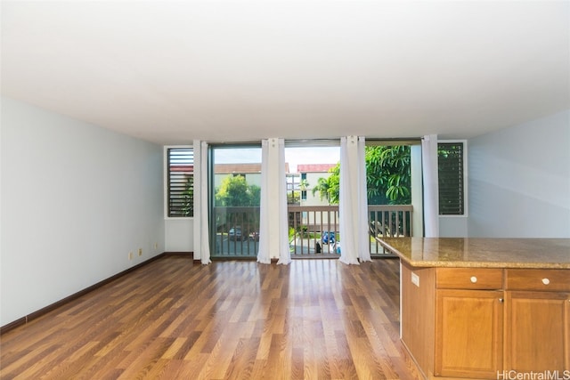 interior space featuring dark wood-type flooring, light stone counters, and floor to ceiling windows