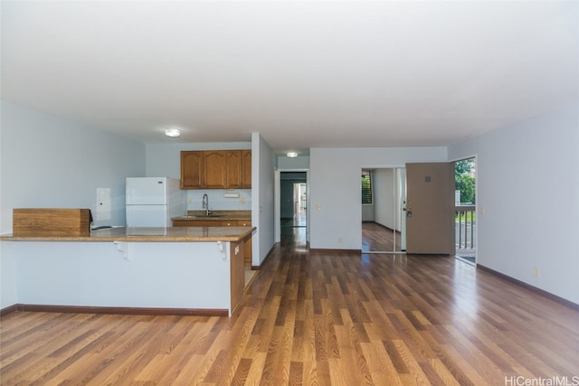 kitchen featuring sink, white fridge, kitchen peninsula, and dark hardwood / wood-style floors