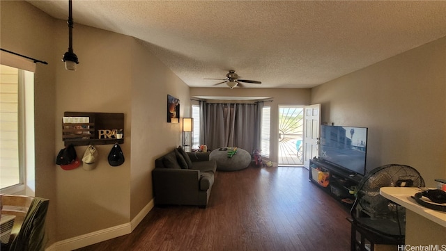 living room featuring ceiling fan, a textured ceiling, and dark hardwood / wood-style flooring