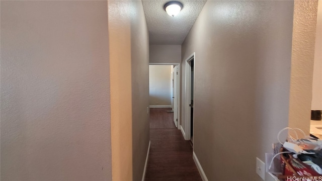 corridor with a textured ceiling and dark wood-type flooring