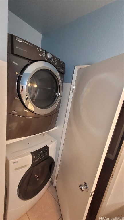 laundry area featuring stacked washer / drying machine and tile patterned flooring