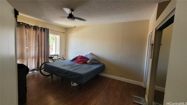 bedroom featuring dark hardwood / wood-style flooring, a textured ceiling, and ceiling fan