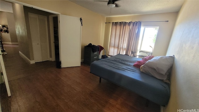 bedroom featuring a closet, a textured ceiling, dark wood-type flooring, and ceiling fan